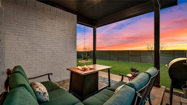 patio terrace at dusk featuring an outdoor living space with a fire pit, a lawn, and a fenced backyard