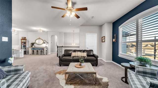 carpeted living area with visible vents, arched walkways, ceiling fan, and baseboards