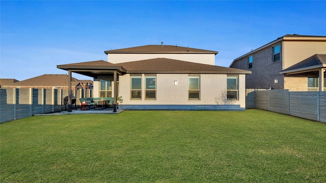 back of house featuring a fenced backyard, a yard, brick siding, and a patio