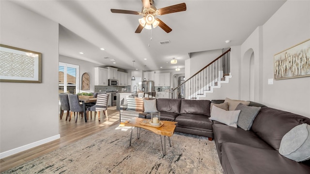 living room featuring recessed lighting, visible vents, baseboards, stairs, and light wood-style floors