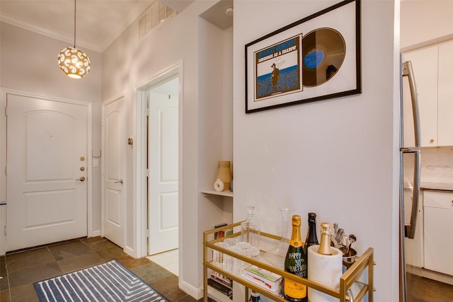 foyer entrance with visible vents, crown molding, and stone finish flooring