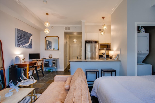 bedroom with visible vents, stacked washer and dryer, freestanding refrigerator, crown molding, and baseboards