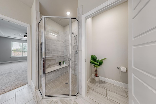 full bathroom with a stall shower, a ceiling fan, and baseboards