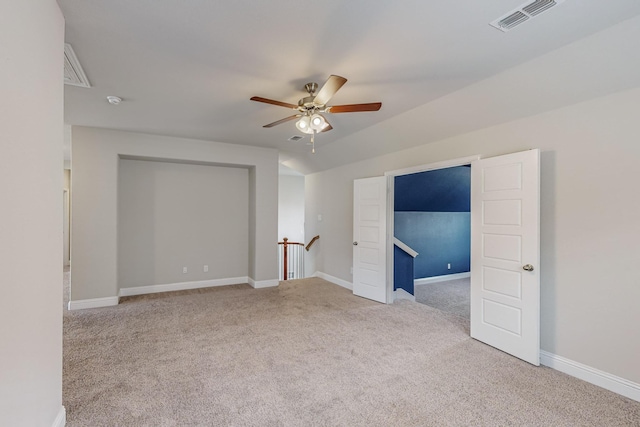 carpeted spare room with baseboards, vaulted ceiling, visible vents, and ceiling fan