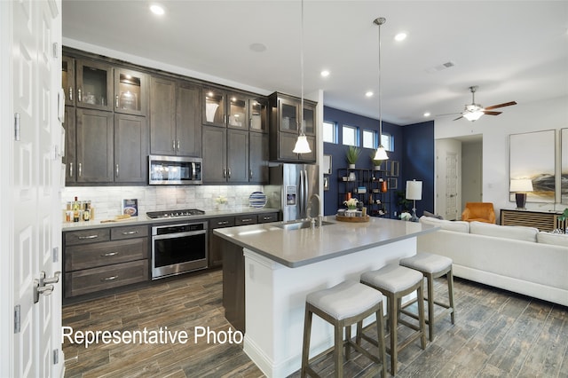 kitchen featuring a breakfast bar, visible vents, decorative backsplash, appliances with stainless steel finishes, and open floor plan