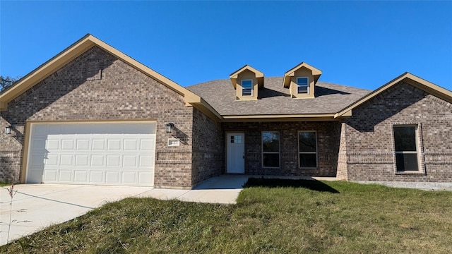 view of front of property with a front yard, concrete driveway, brick siding, and an attached garage