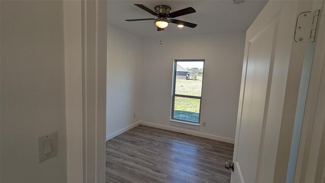 empty room featuring ceiling fan, baseboards, and wood finished floors