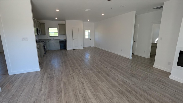 unfurnished living room with light wood finished floors, visible vents, and baseboards