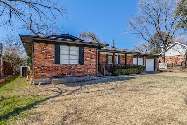 view of front of house with a garage, concrete driveway, cooling unit, a front lawn, and brick siding