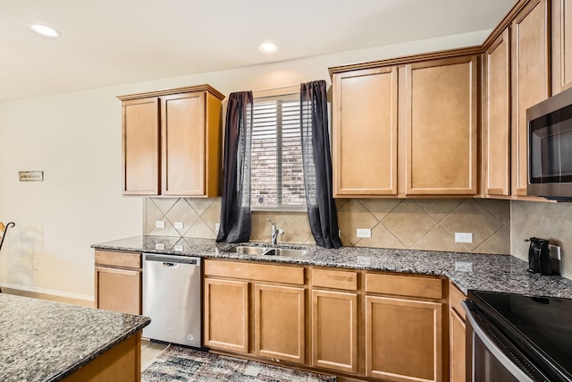 kitchen with tasteful backsplash, appliances with stainless steel finishes, dark stone counters, and a sink