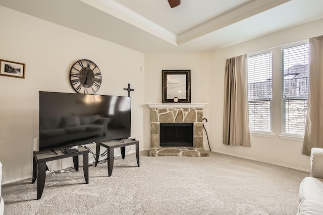 carpeted living room featuring crown molding, a tray ceiling, a fireplace, and a healthy amount of sunlight