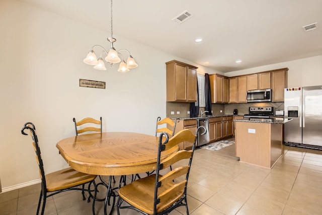 kitchen featuring appliances with stainless steel finishes, a center island, visible vents, and backsplash