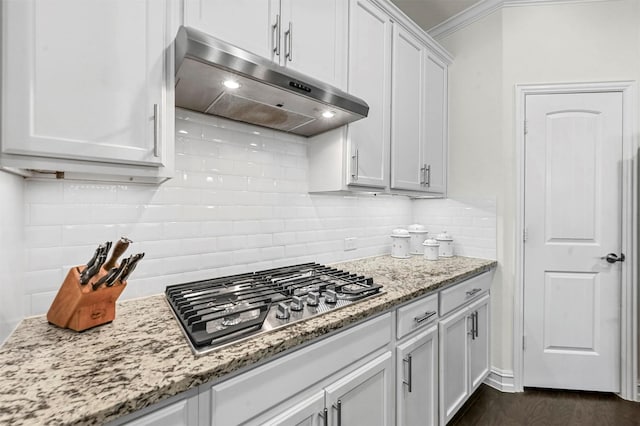 kitchen featuring white cabinets, crown molding, under cabinet range hood, stainless steel gas stovetop, and backsplash