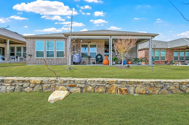 back of house featuring brick siding and a lawn