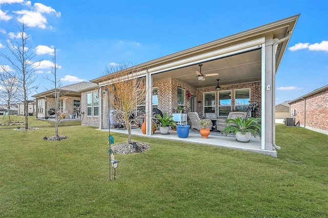 back of property featuring brick siding, a yard, a patio, a ceiling fan, and cooling unit