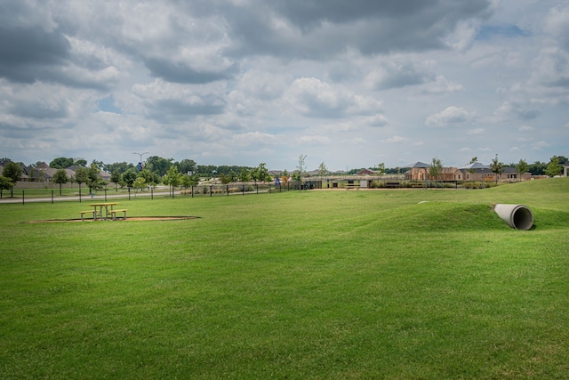 view of property's community featuring a lawn and fence