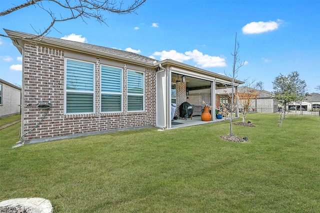 back of house with a patio area, brick siding, and a lawn