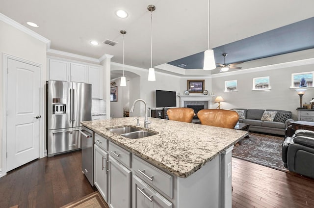 kitchen with a fireplace, visible vents, appliances with stainless steel finishes, open floor plan, and a sink