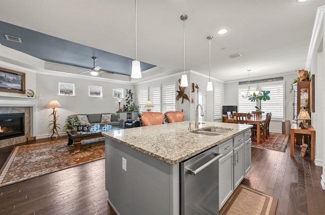 kitchen featuring visible vents, a tile fireplace, a sink, a tray ceiling, and stainless steel dishwasher