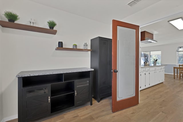 interior space with visible vents, baseboards, light wood-style floors, white cabinets, and open shelves