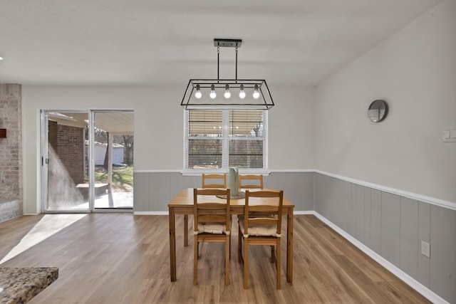 dining space with wood finished floors and wainscoting