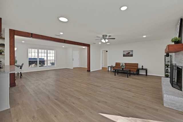 living room featuring recessed lighting, a fireplace, baseboards, and light wood finished floors