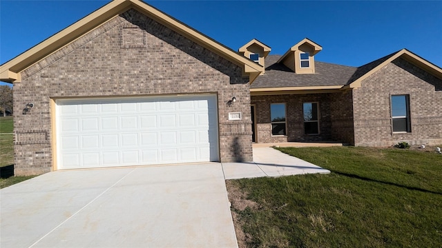 view of front of property with a garage, brick siding, driveway, and a front lawn