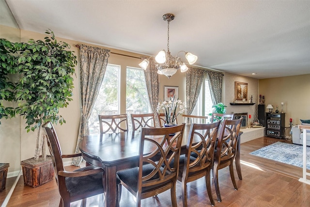 dining area featuring a notable chandelier, a fireplace, and wood finished floors