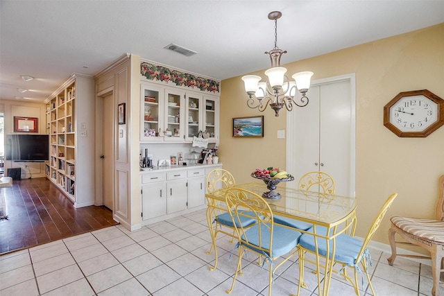 dining area featuring light tile patterned floors, baseboards, visible vents, and a notable chandelier