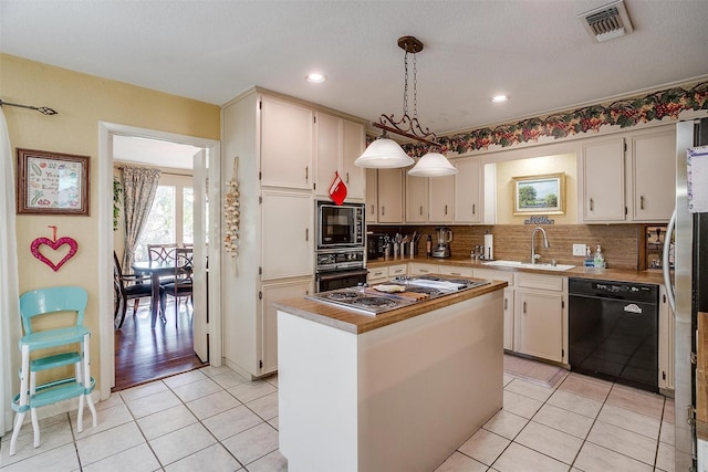 kitchen featuring light tile patterned floors, a sink, visible vents, decorative backsplash, and black appliances