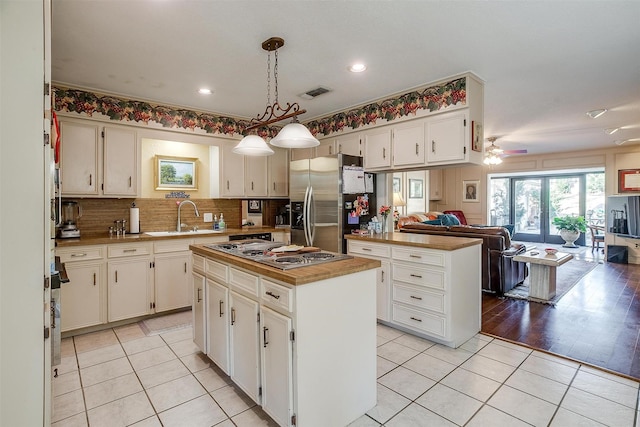 kitchen featuring light tile patterned flooring, stainless steel appliances, a sink, visible vents, and open floor plan