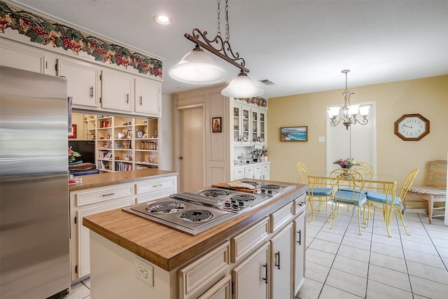 kitchen with a notable chandelier, light tile patterned floors, stainless steel appliances, visible vents, and white cabinets