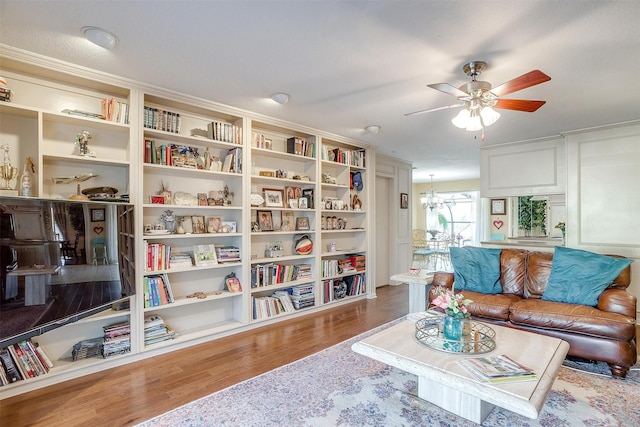 living area with ceiling fan with notable chandelier and wood finished floors