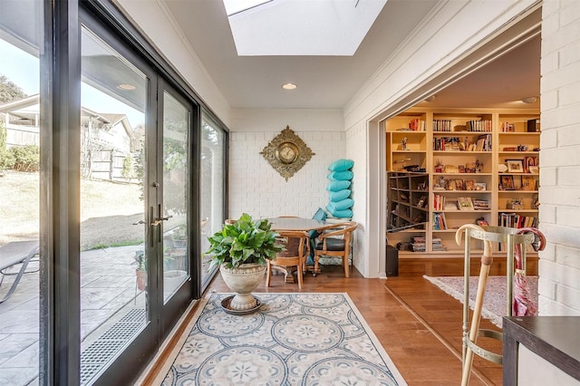 interior space featuring a skylight, brick wall, and wood finished floors