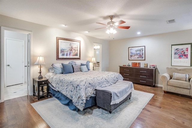 bedroom featuring baseboards, wood finished floors, visible vents, and a ceiling fan