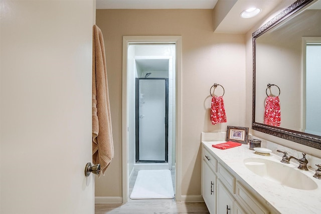 bathroom featuring a stall shower, baseboards, wood finished floors, and vanity