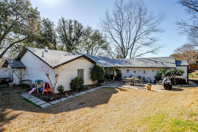 rear view of house with a yard, a patio area, and a playground