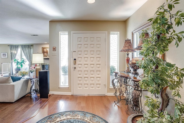 entrance foyer featuring baseboards, visible vents, and wood finished floors