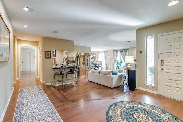 living room with recessed lighting, wood finished floors, visible vents, and baseboards