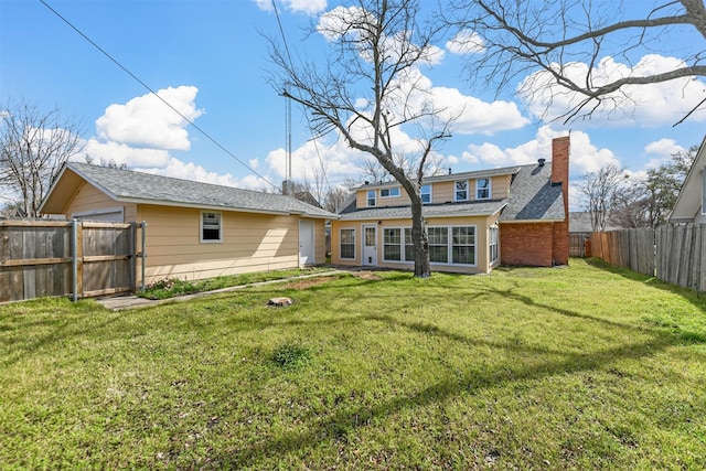 rear view of property with a yard, a fenced backyard, brick siding, and a chimney