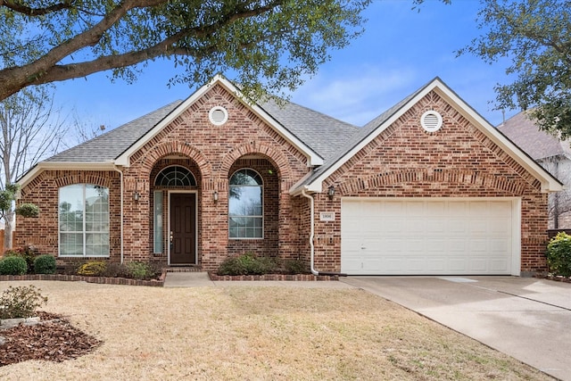 view of front facade with driveway, a shingled roof, a garage, and brick siding