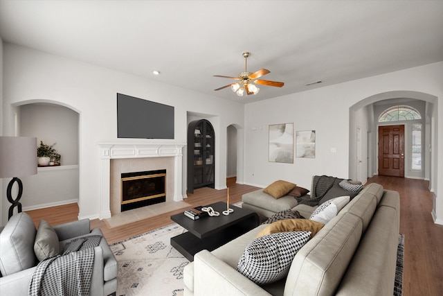 living room with light wood-type flooring, a fireplace with flush hearth, visible vents, and baseboards