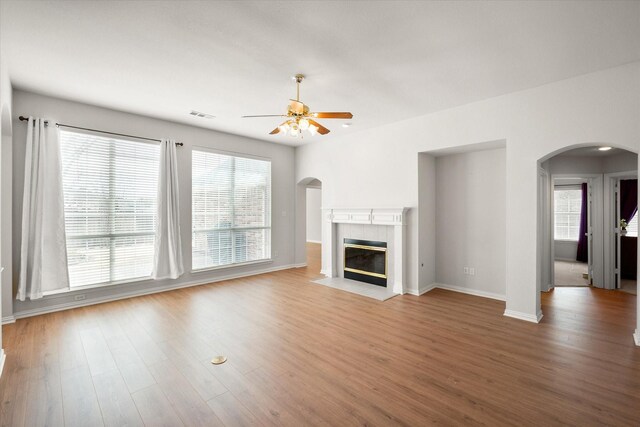 living area featuring light wood finished floors, a fireplace with flush hearth, visible vents, and baseboards