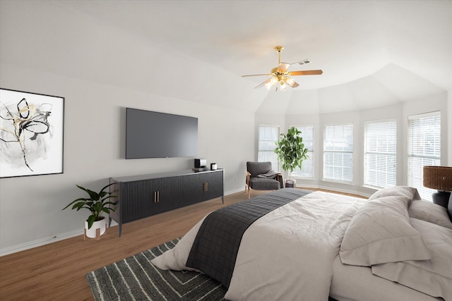 bedroom featuring a ceiling fan, multiple windows, baseboards, and wood finished floors