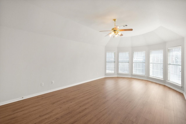 unfurnished room with lofted ceiling, visible vents, a ceiling fan, wood finished floors, and baseboards