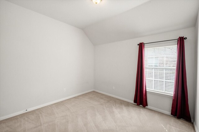 bedroom featuring lofted ceiling, light carpet, and baseboards