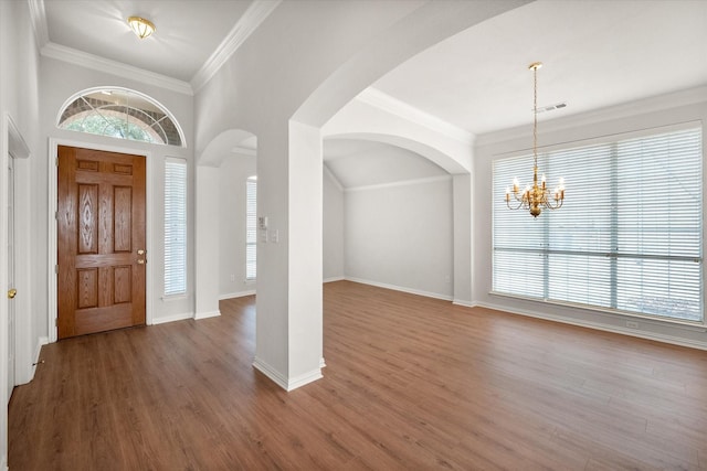 foyer featuring wood finished floors, visible vents, baseboards, an inviting chandelier, and crown molding