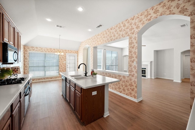 kitchen featuring visible vents, a sink, black appliances, and wallpapered walls