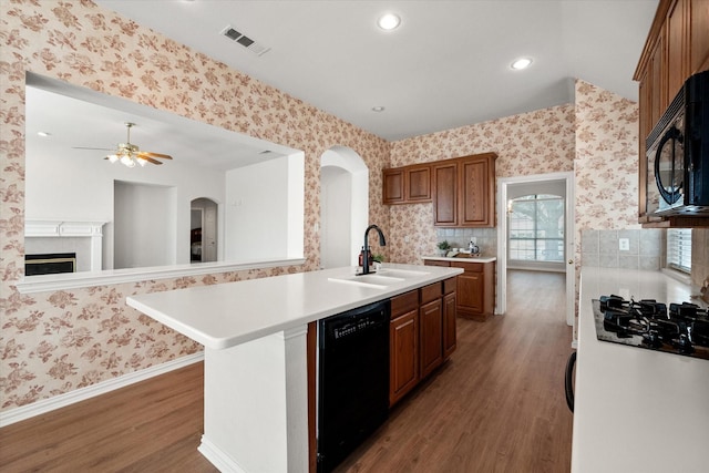 kitchen with visible vents, a sink, black appliances, and wallpapered walls