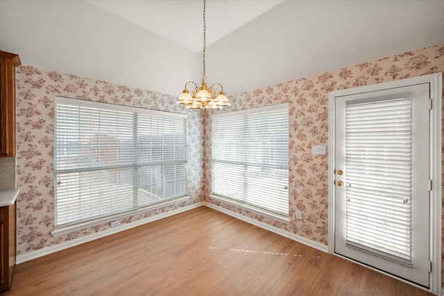 unfurnished dining area featuring a chandelier, baseboards, light wood finished floors, and wallpapered walls